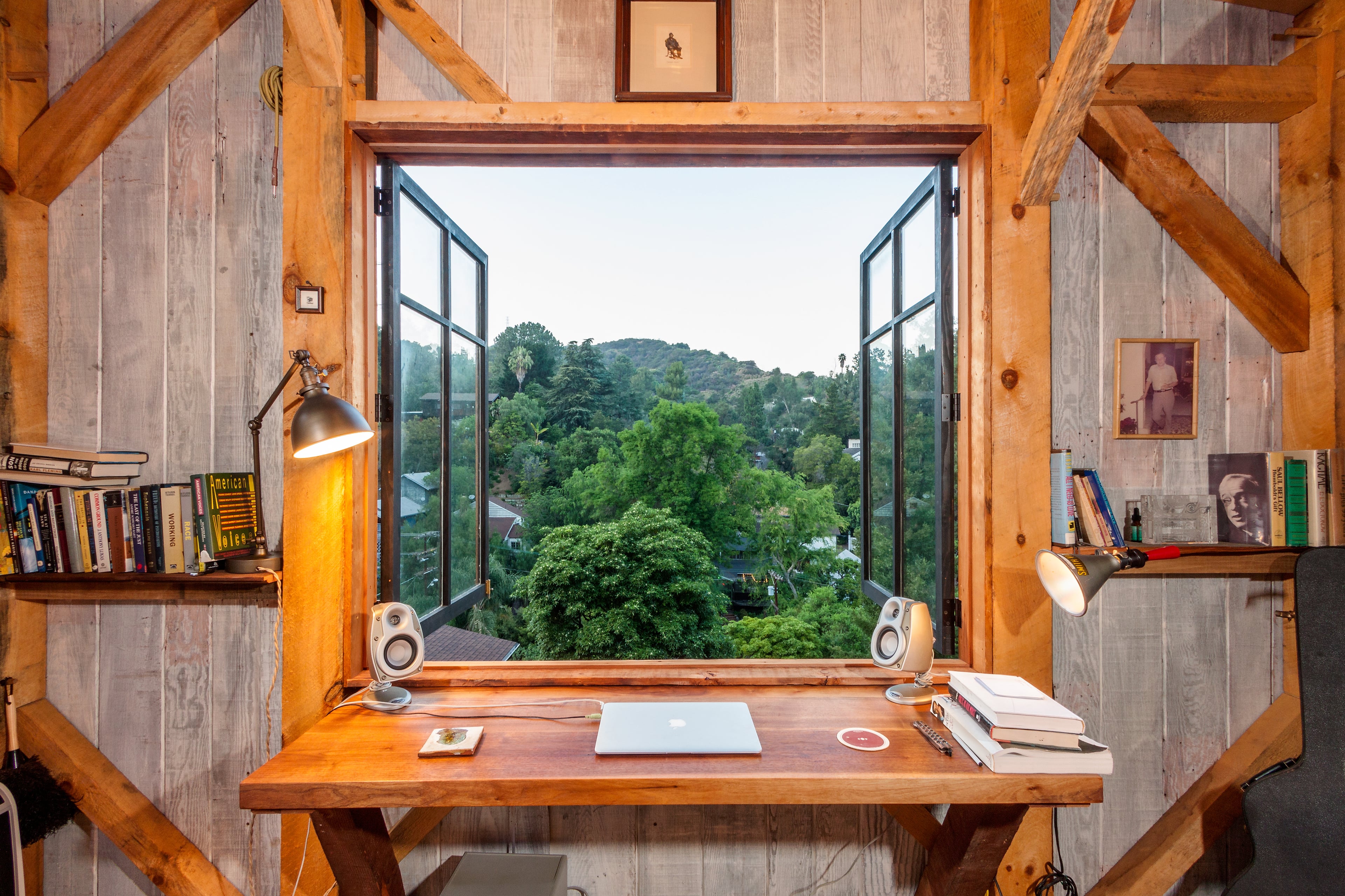 A writing desk in a wood-paneled hillside study, looking out over the trees of Los Angeles.